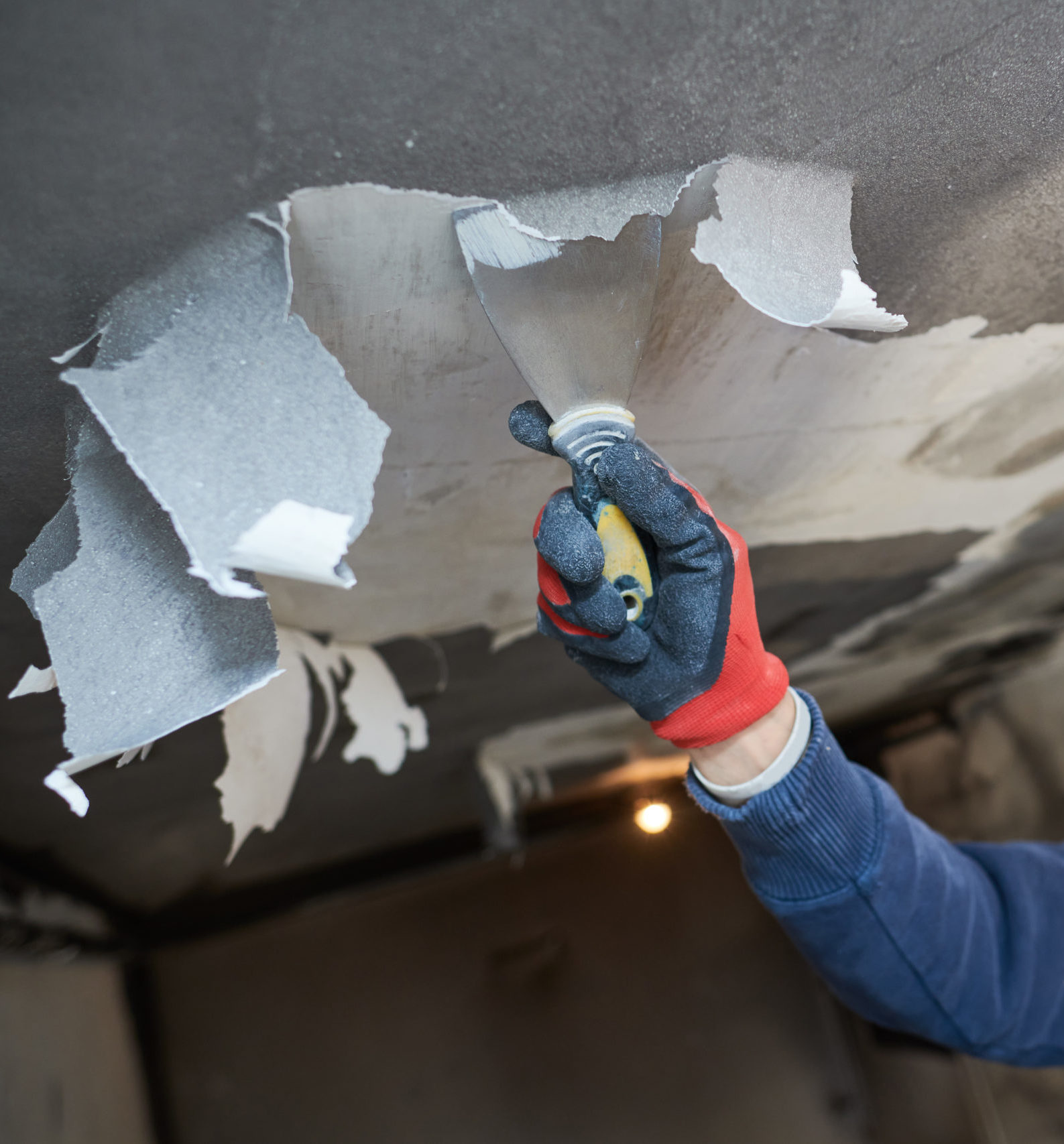 A person in blue gloves is holding something up to the ceiling.
