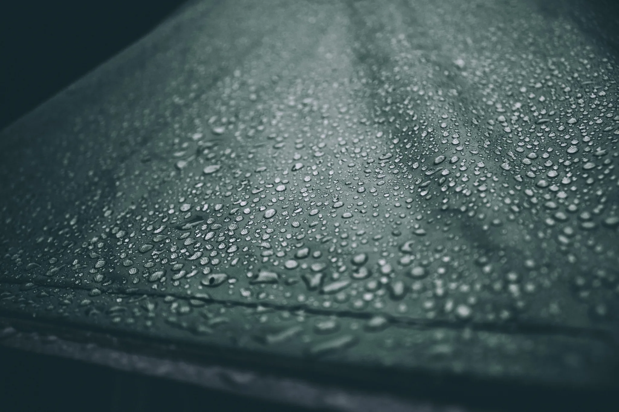 A close up of water droplets on the surface of a car.
