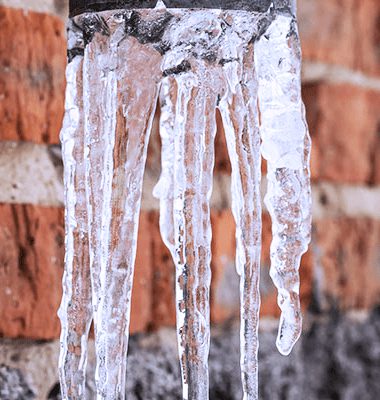 winter-weather-ice A close up of icicles hanging from the side of a brick wall.